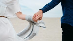 man and woman holding hands together in field during daytime