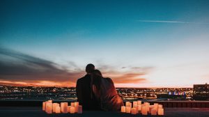 couple sitting on the field facing the city